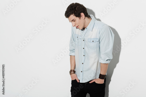 Insecurity. An attractive male standing awkwardly with his hands in his pockets looking down with copyspace. photo
