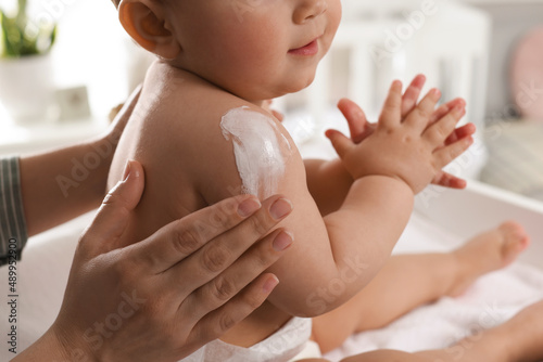 Foto Mother applying body cream on her little baby at home, closeup