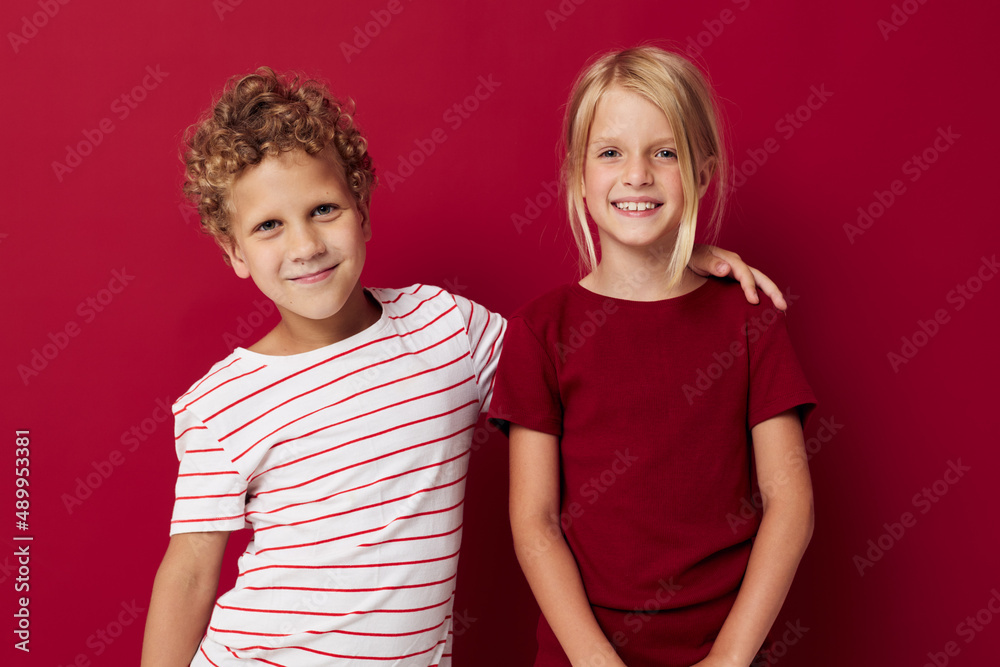 Cute preschool kids smiling and posing in casual clothes against red background Cute preschool kids smiling and posing in casual clothes against red background
