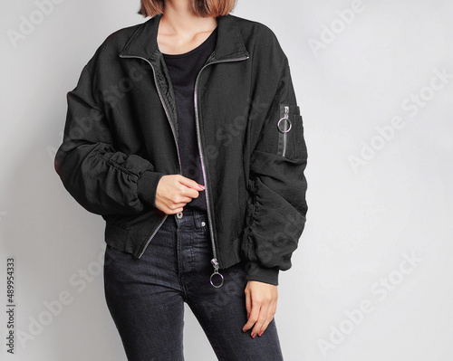 Obraz na plátně Woman wearing black bomber jacket and black jeans isolated on white background