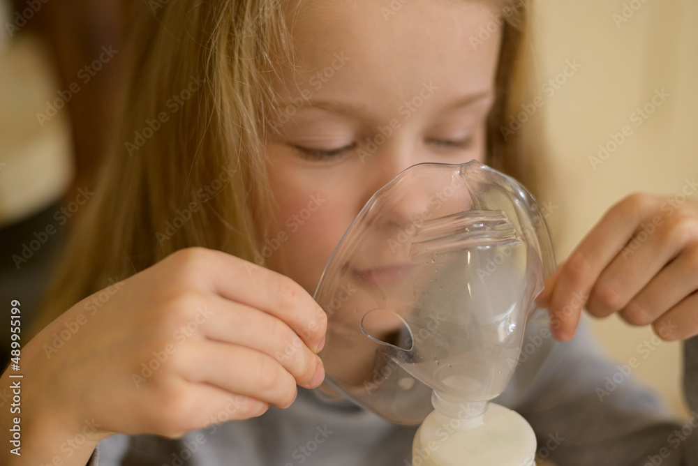 a sick child makes inhalation with a nebulizer at home: he holds a mask from which steam. The child is not feeling well. Health a sick child makes inhalation with a nebulizer at home: he holds a mask from which steam. The child is not feeling well. Health