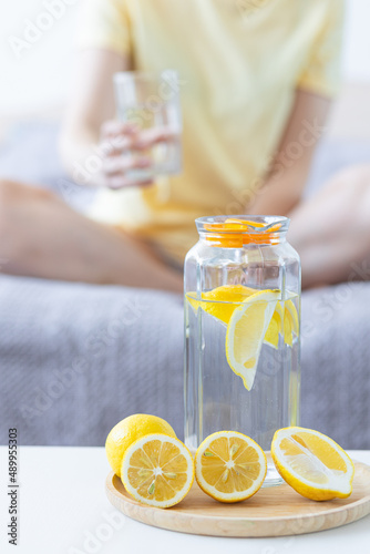Healthy drink - water with lemon. Female drinking from the glass on background. Concept of clean eating, low calories, weight loss, dieting. Natural organic morning beverage