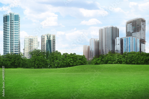 Beautiful view of park with green lawn and cityscape on sunny day © New Africa