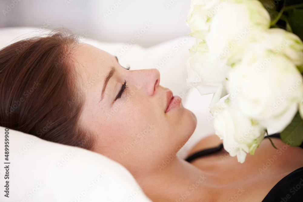 A sleeping beauty. A beautiful young woman lying down with closed eyes and holding a bouquet of white roses to her chest. A sleeping beauty. A beautiful young woman lying down with closed eyes and holding a bouquet of white roses to her chest.
