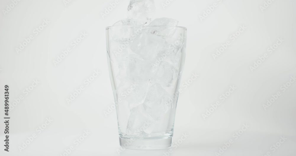 Ice cubes fall in glass isolated white cool close up in slow motion Ice cubes fall in glass isolated white cool close up in slow motion