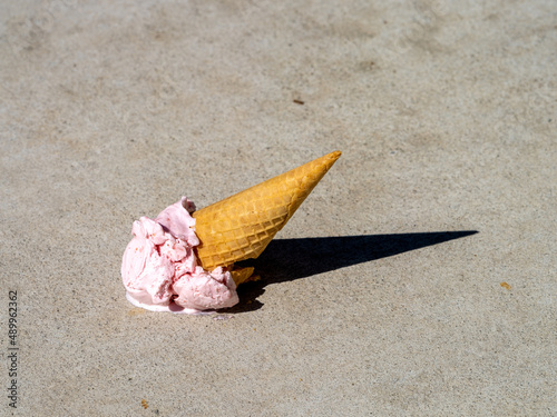 Strawberry Ice Cream cone melting after being dropped onto the ground. photo