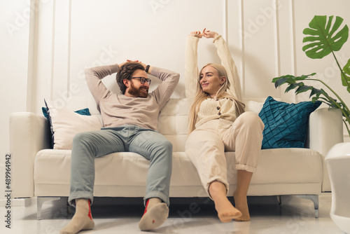 caucasian couple relaxing and stretching their arms on a sofa placed in their renovated living room. High quality photo photo