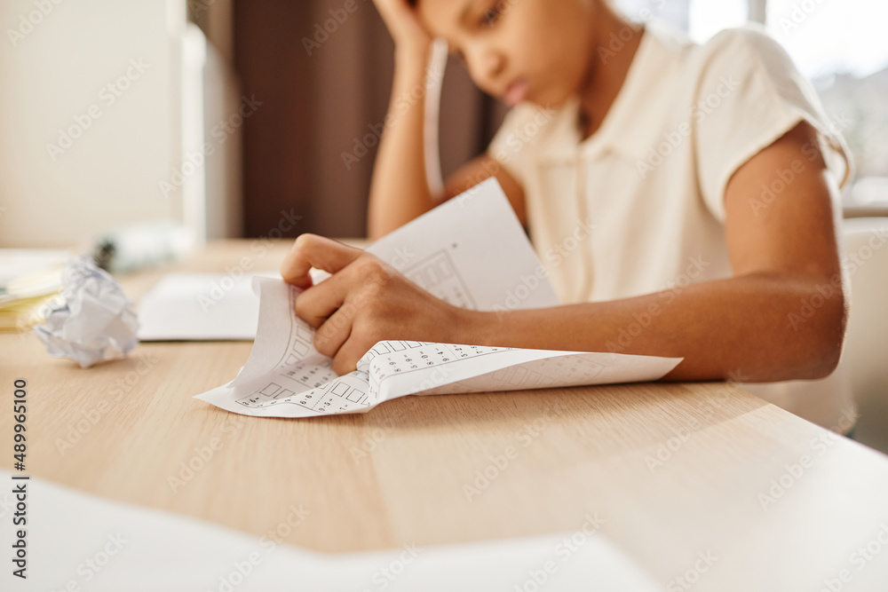 Close up of anxious child crumpling homework while struggling with school work, copy space Close up of anxious child crumpling homework while struggling with school work, copy space