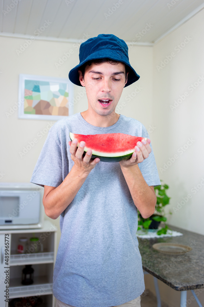 Man eating a piece of watermelon in his home kitchen. Man eating a piece of watermelon in his home kitchen.