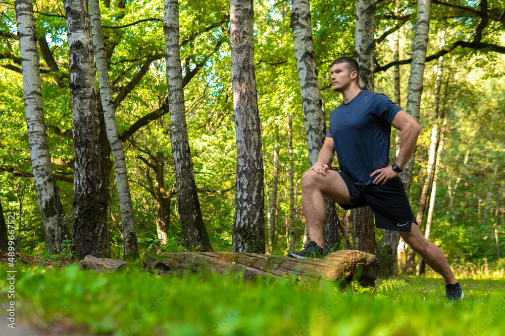 A young enduring athletic athlete is doing stretching in the forest outdoors, around the forest, oak trees.run sport exercise, lifestyle outdoor endurance recreation jog, outside. Autumn energy spring