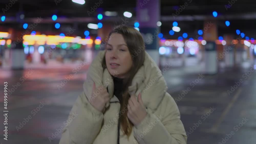 Young woman walking and looking at camera in underground parking garage. Young woman walking and looking at camera in underground parking garage.