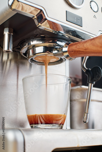 Making coffee, coffee extraction process using espresso machine, espresso machine pouring coffee into cup. vertical