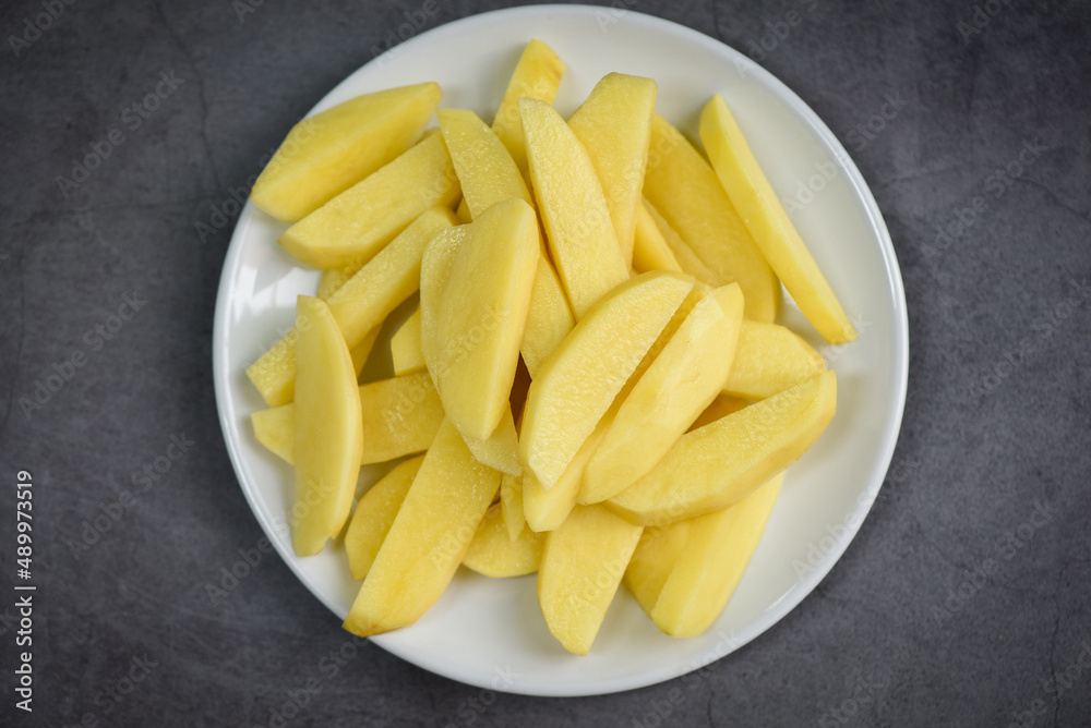 fresh raw potato wedges, chopped potatoes for cooked food on white plate fresh raw potato wedges, chopped potatoes for cooked food on white plate