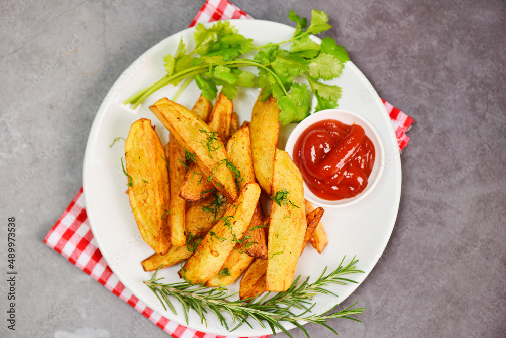 Potato wedges on white plate with rosemary herb coriander and tomato ketchup sauce, Cooking french fries or fry potatoes Potato wedges on white plate with rosemary herb coriander and tomato ketchup sauce, Cooking french fries or fry potatoes