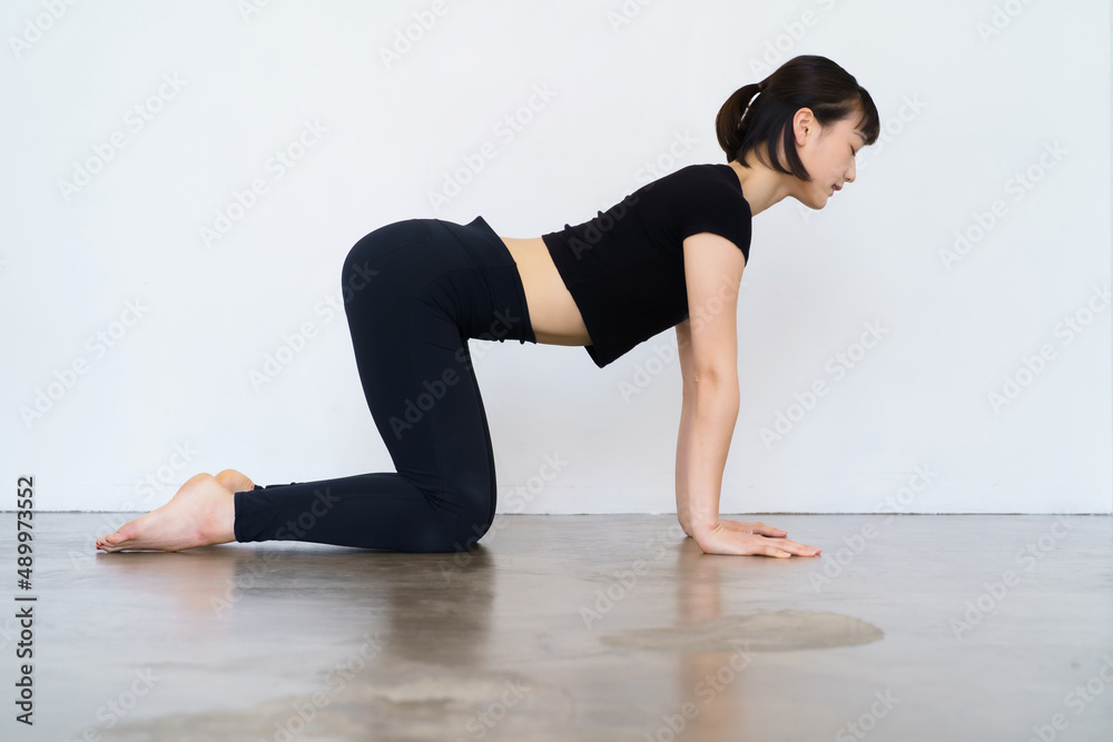 Naklejka premium ヨガ（牛のポーズ・猫のポーズ）をする女性 