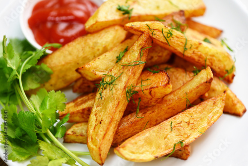 Potato wedges on white plate with rosemary herb coriander and tomato ketchup sauce, Cooking french fries or fry potatoes