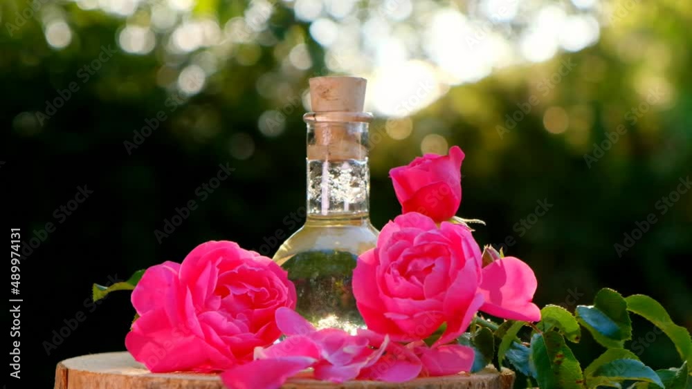 Rose essential oil in a glass bottle in rose flowers on a wooden saw cut. High quality 4k footage Rose essential oil in a glass bottle in rose flowers on a wooden saw cut. High quality 4k footage