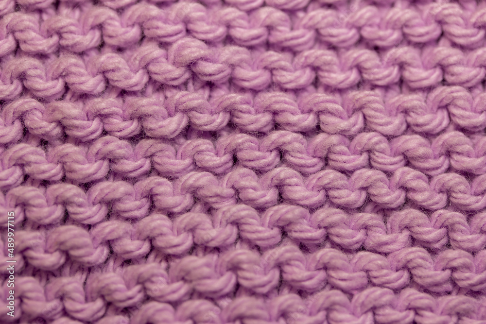 Macro abstract background of hand-knitted yarn fabric texture with a garter stitch pattern, in the color of dusty rose