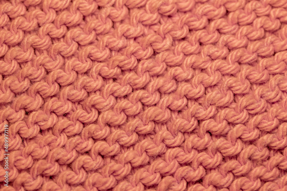 Macro abstract background of hand-knitted yarn fabric texture with a garter stitch pattern, in the color of salmon orange Macro abstract background of hand-knitted yarn fabric texture with a garter stitch pattern, in the color of salmon orange