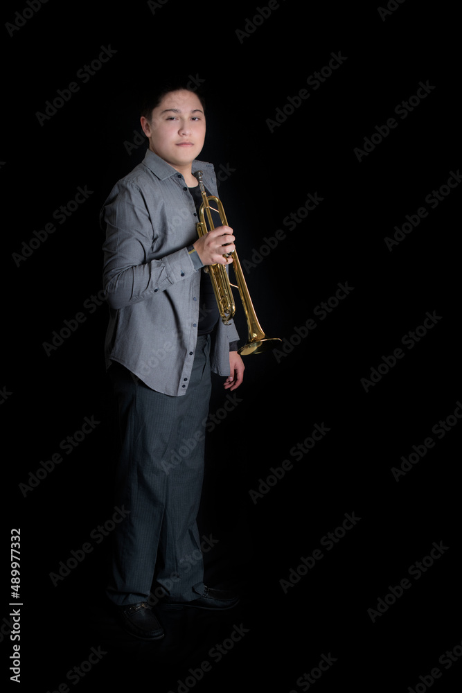 Naklejka premium Young teenager energetically playing trumpet on black background