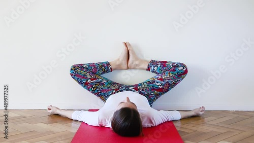 Yogui white woman in a butterfly or shoemaker inverted posture with wall