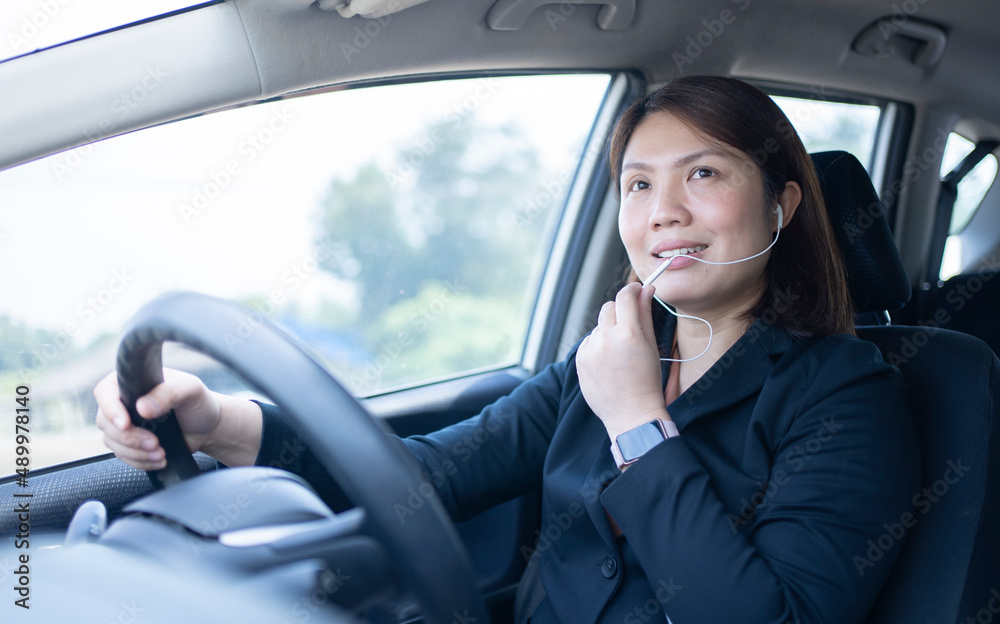 Businesswoman using earphone for talking business in a car on driving