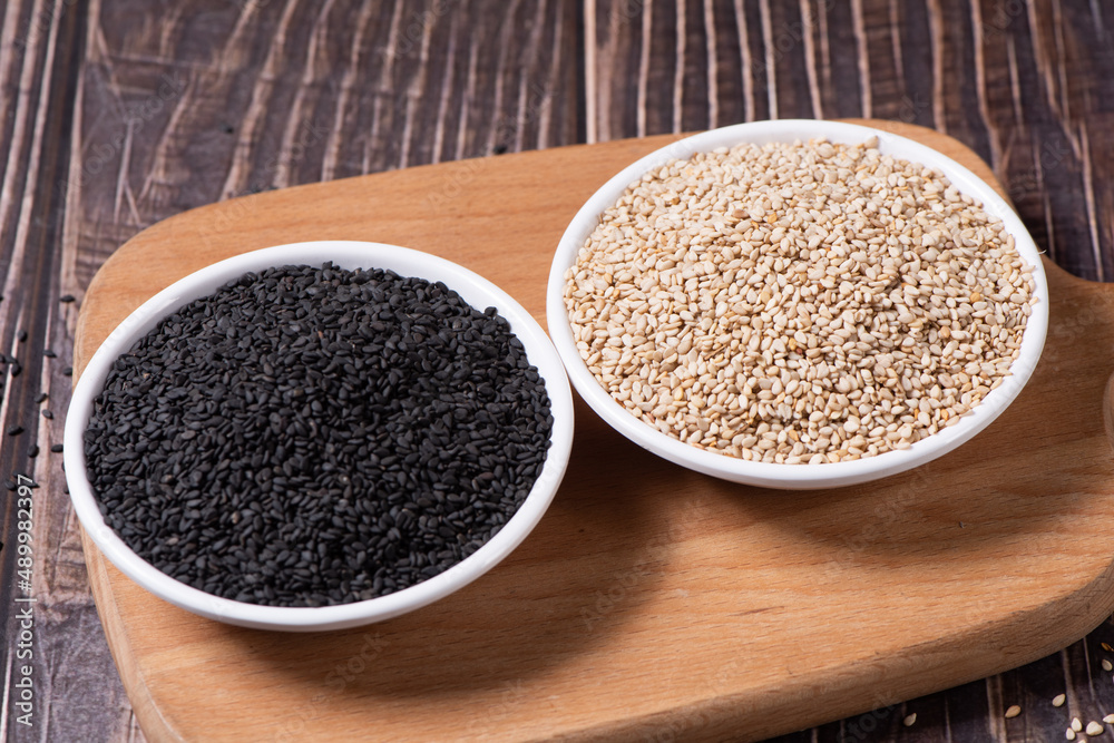 White sesame seed and black sesame in a plate on wooden table White sesame seed and black sesame in a plate on wooden table