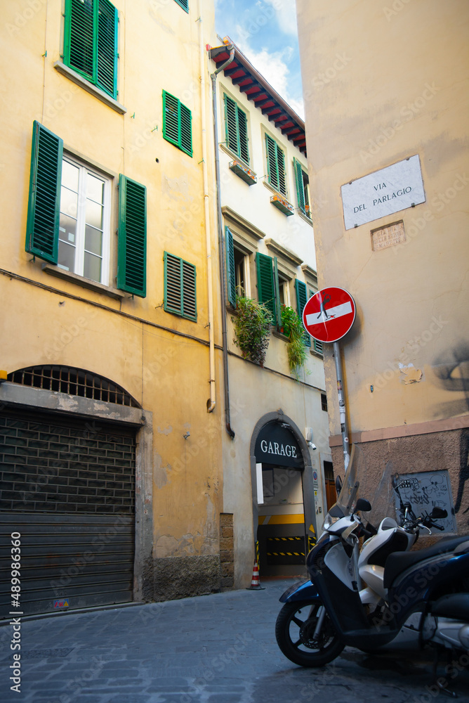 A street in Florence Italy where mopeds are parked.  blue sky as background.