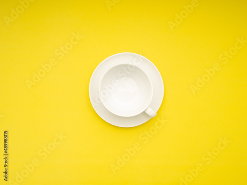 Top view of an empty white ceramic coffee cup on a yellow background
