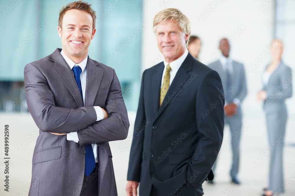 Business men with colleagues in background. Portrait of smiling business men with colleagues in background.
