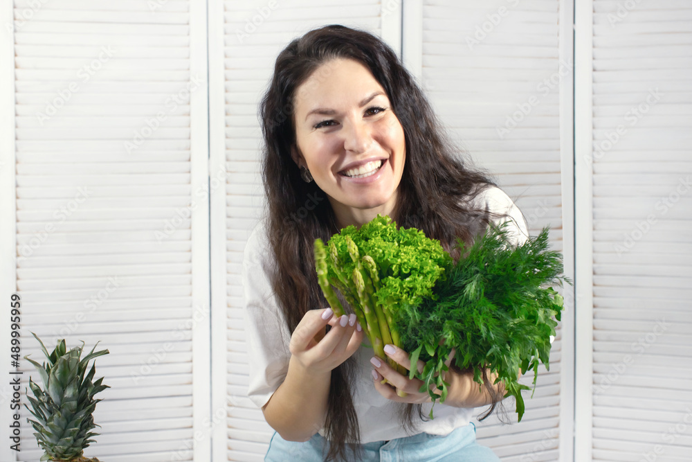 Smiling woman with salad leaves, celery and dill with parsley. Spring and vitamins. The concept of healthy nutrition. Front photo. Smiling woman with salad leaves, celery and dill with parsley. Spring and vitamins. The concept of healthy nutrition. Front photo.