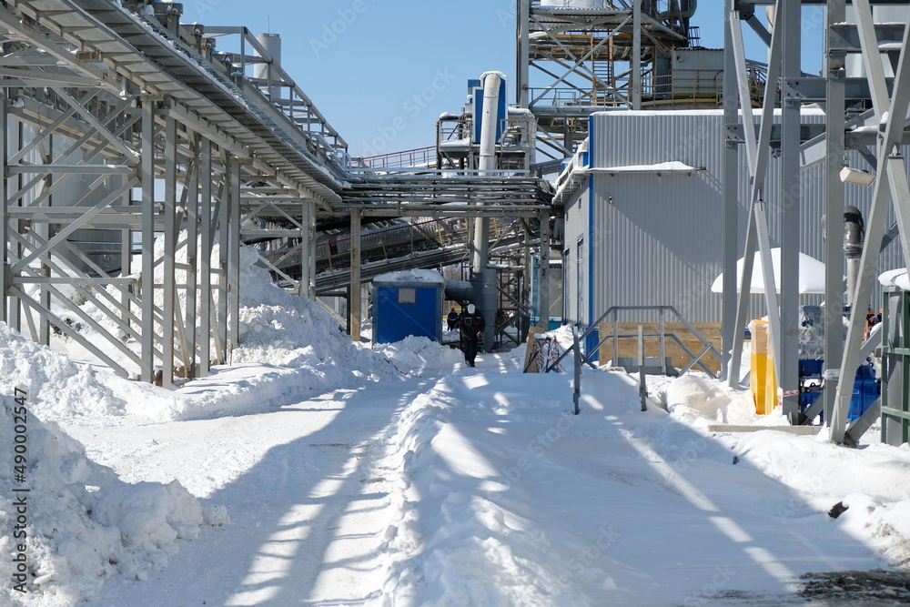 Fototapeta premium Magadan / Russia - 03.20.2019 : Workers in overalls pass through the territory of the metallurgical plant