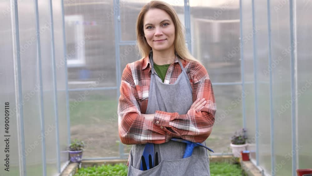 Female farmer owner working in vegetables hydroponic farm with happiness. Young woman is crossing arm and looking at camera with smile in the green house farm. Concept of farming Female farmer owner working in vegetables hydroponic farm with happiness. Young woman is crossing arm and looking at camera with smile in the green house farm. Concept of farming