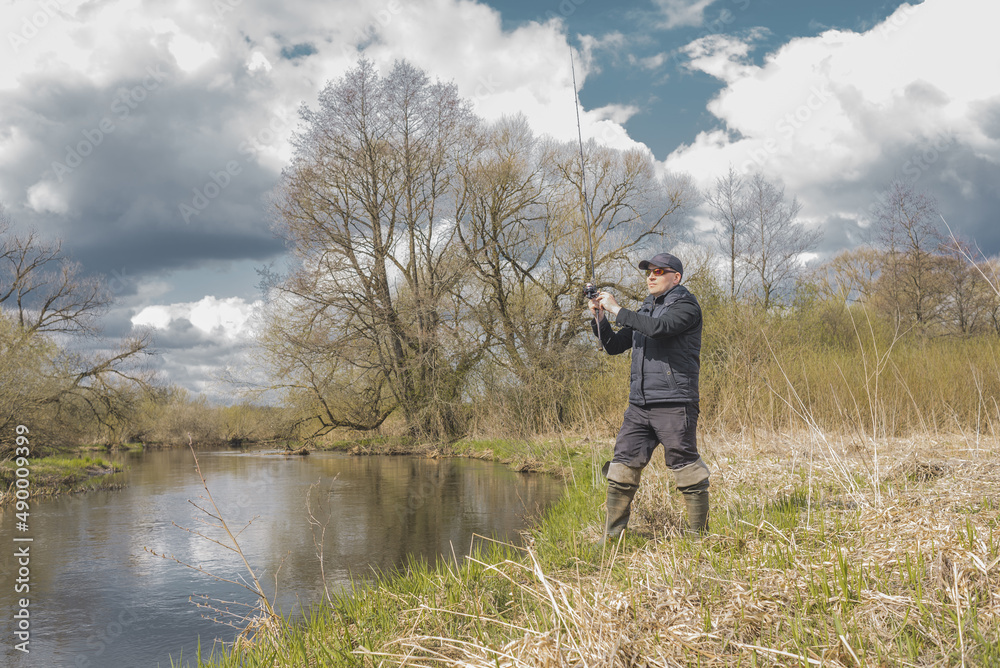 Man is fishing on a spinning rod from the shore. Man is fishing on a spinning rod from the shore.