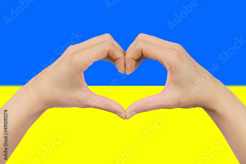 female hands in the shape of a heart on the background of the Ukrainian flag.