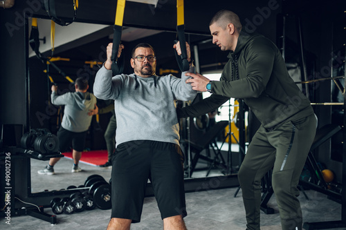 Middle aged men with fitness trainer exercising at the gym