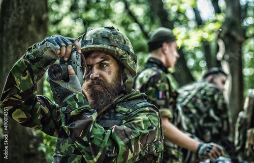 Photojournalist documenting war, military press photographer. Military operation. Shooting with assault rifle and machine gun, attacking enemy. Military photo, army background.