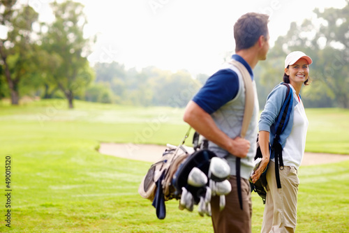 Female golfer smiling and looking at man. Focus on female golfer smiling and looking at man.