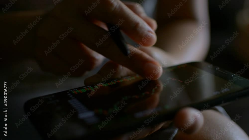 Close up fingers of businesswoman scrolling on mobile phone touchscreen. Checking stock market data. Stock market graph simulator on a smartphone screen. Business and finance. Close up fingers of businesswoman scrolling on mobile phone touchscreen. Checking stock market data. Stock market graph simulator on a smartphone screen. Business and finance.