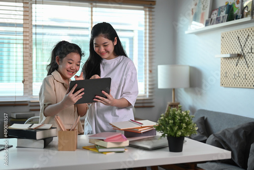 Two asian girl doing online homework or surfing internet with digital tablet at home.