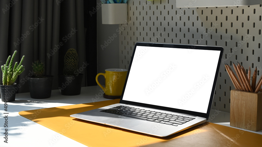 Computer laptop, pencil holder, coffee cup and potted plant on white table. Blank screen for advertisement. Computer laptop, pencil holder, coffee cup and potted plant on white table. Blank screen for advertisement.