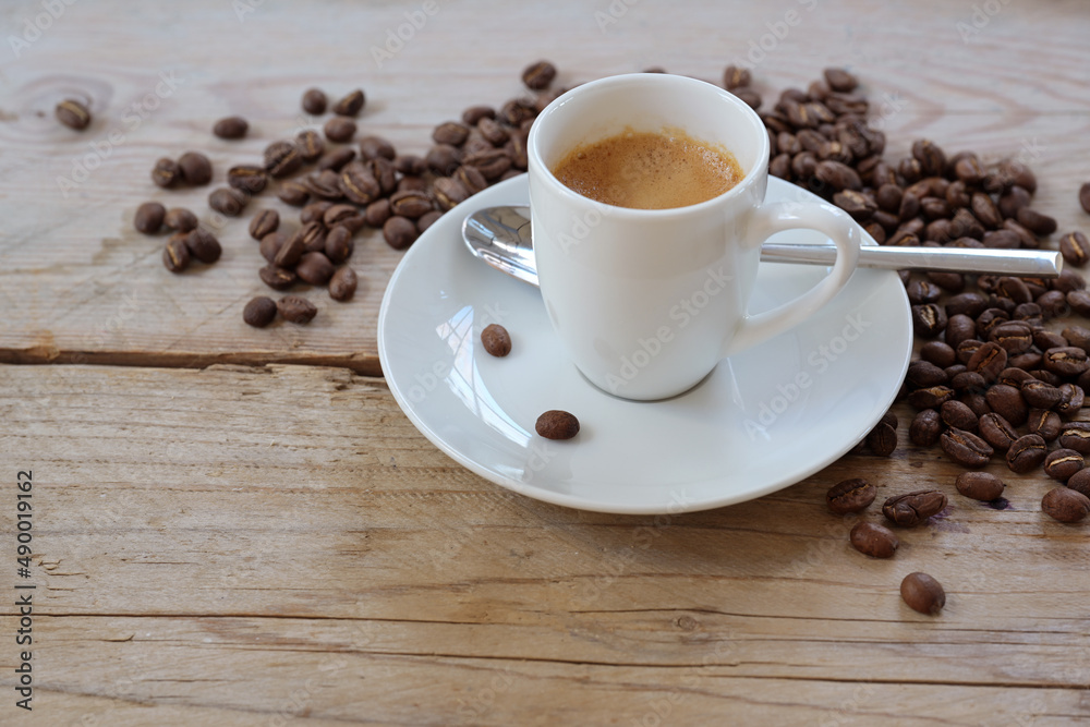 Espresso in a small white coffee cup and some roasted beans on rustic wooden planks, copy space, selected focus Espresso in a small white coffee cup and some roasted beans on rustic wooden planks, copy space, selected focus