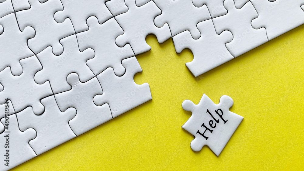 Obraz premium Help word on a jigsaw puzzle with yellow background.