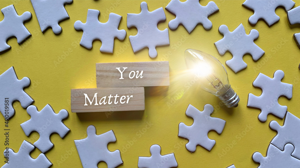 Obraz premium Top view of words - You matter with light bulb and jigsaw puzzle background.