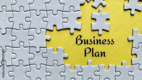 Business plan text on yellow background with white jigsaw puzzle missing pieces.