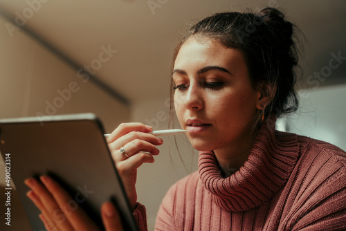 caucasian female student working from home on digital tablet