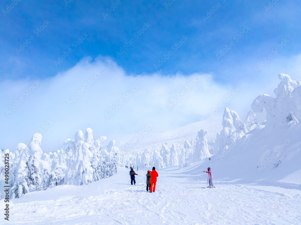 Snow monsters (soft rime) plateau peeking through thick clouds and people looking back at them (Zao-onsen ski resort, Yamagata, Japan)