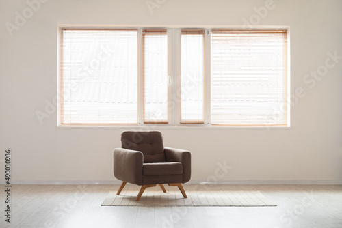 View of light wall with window and armchair in empty room