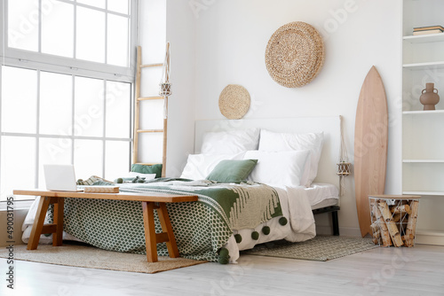 Photography Interior of light bedroom with wooden surfboard and bench