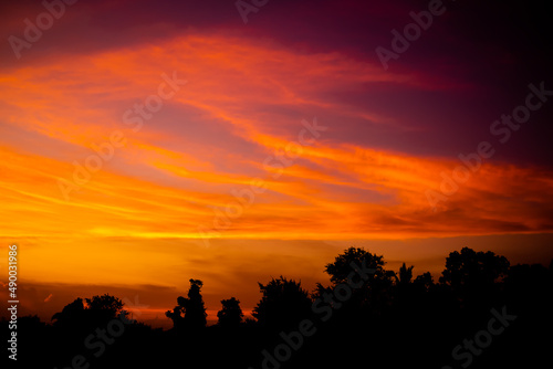 Evening Sky, twilight dramatic gold sunset dusk with silhouette dark black tree in night background. colorful sunlight cloud sky pastel bright yellow orange backdrop. nature landscape beautiful.